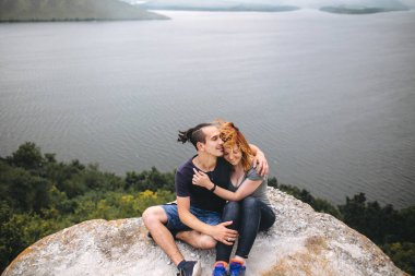 Güzel ile kaya dağın tepesinde oturan mutlu hipster çift