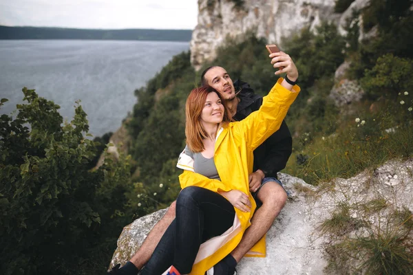 Feliz pareja hipster tomando selfie en el teléfono en la parte superior de montaje en roca — Foto de Stock
