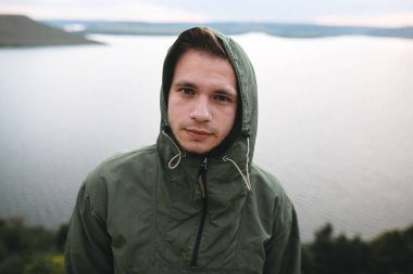 Kayanın tepesinde yeşil rüzgarlık hipster gezgin portresi