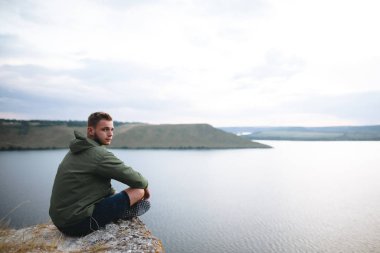 Hipster gezgin kaya dağın tepesinde oturan ve zevk