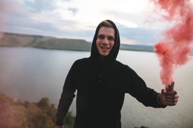 Elinde kırmızı sis bombası tutan şık hipster, üstünde duruyor 