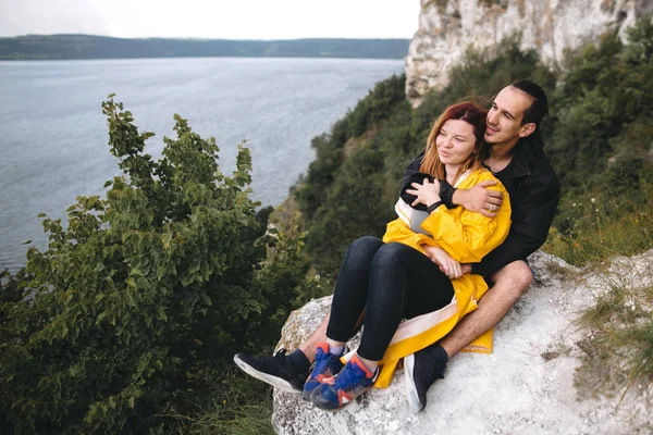 Feliz pareja hipster en impermeables sentados en la cima de la roca mountai — Foto de Stock