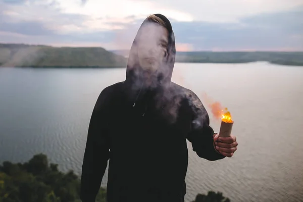 Stylish hipster guy holding smoke bomb with burning fire in hand — Stock Photo, Image