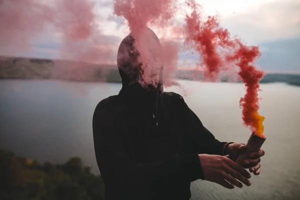 Ultras hooligan holding red smoke bomb in hand, standing on top — Stock Photo, Image