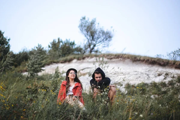 Hipster pareja sentado en la cima de roca montaña en la hierba y enjo — Foto de Stock