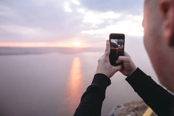 Hipster viajero tomando fotos en el teléfono de increíble puesta de sol vista en — Foto de Stock