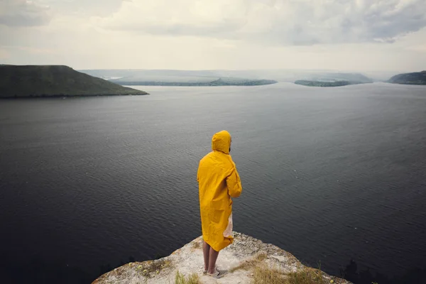 Wanderlust and travel concept. Hipster traveler in yellow rainco — Stock Photo, Image
