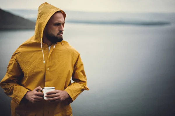 Atmospheric moment. Hipster traveler in yellow raincoat holding