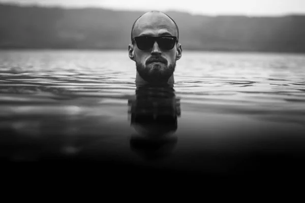 戴着太阳镜的胡须男子在湖浪中浮现出来。人头 — 图库照片