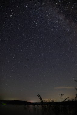 Dağlarda gölün üzerinde inanılmaz yıldızlı gece gökyüzü. Güzel nigh