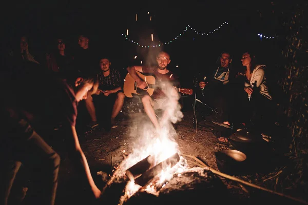 Hipster hombre tocando en la guitarra acústica y cantando canción con fri —  Fotos de Stock