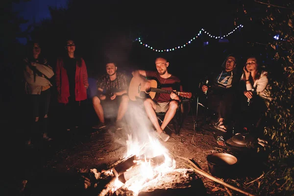 Amis voyageurs se refroidissant au grand feu de joie, à l'écoute acoustique — Photo