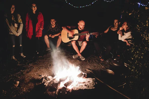 Hipster hombre tocando en la guitarra acústica y cantando canción con fri —  Fotos de Stock