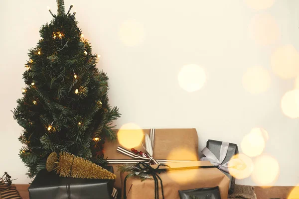 Árbol de Navidad en luces doradas bokeh con regalos elegantes festivos — Foto de Stock