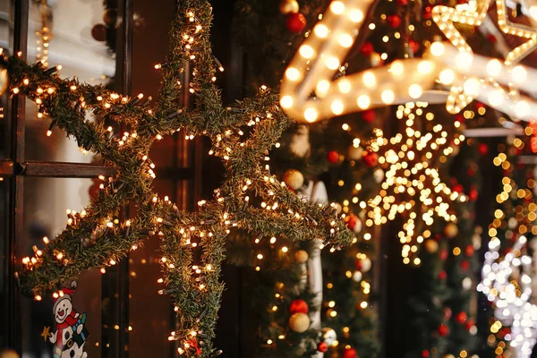 Elegante estrella de Navidad iluminada y ramas de abeto con rojo y — Foto de Stock