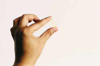 El beyaz duvar arka plan üzerinde omega 3 kapsül tutarak. Sabah d