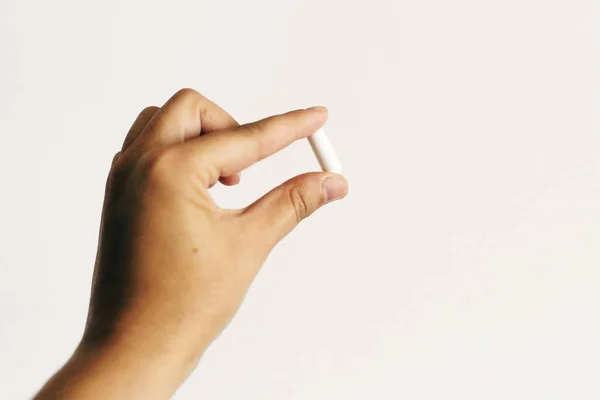 Cápsula de magnesio de mano sobre fondo blanco de pared. Alimentación — Foto de Stock