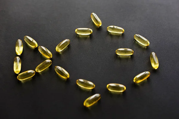 Concepto Omega 3. Cápsulas Omega en forma de pez sobre dorso negro oscuro — Foto de Stock