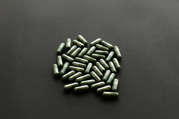 Cápsulas de espirulina sobre fondo negro oscuro. Suplementos alimenticios — Foto de Stock