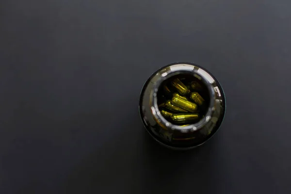 Spirulina cápsulas em frasco frasco sobre fundo preto escuro. Plano — Fotografia de Stock