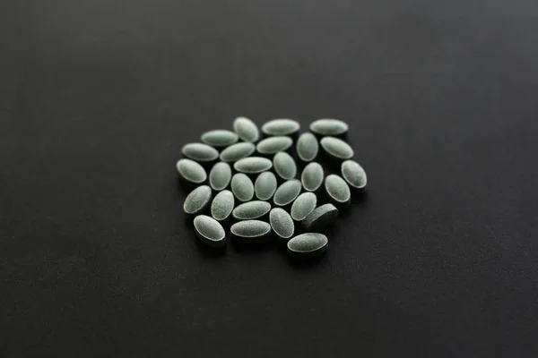 Tabletki chlorofilu na czarnym ciemnym tle. Suplement diety — Zdjęcie stockowe