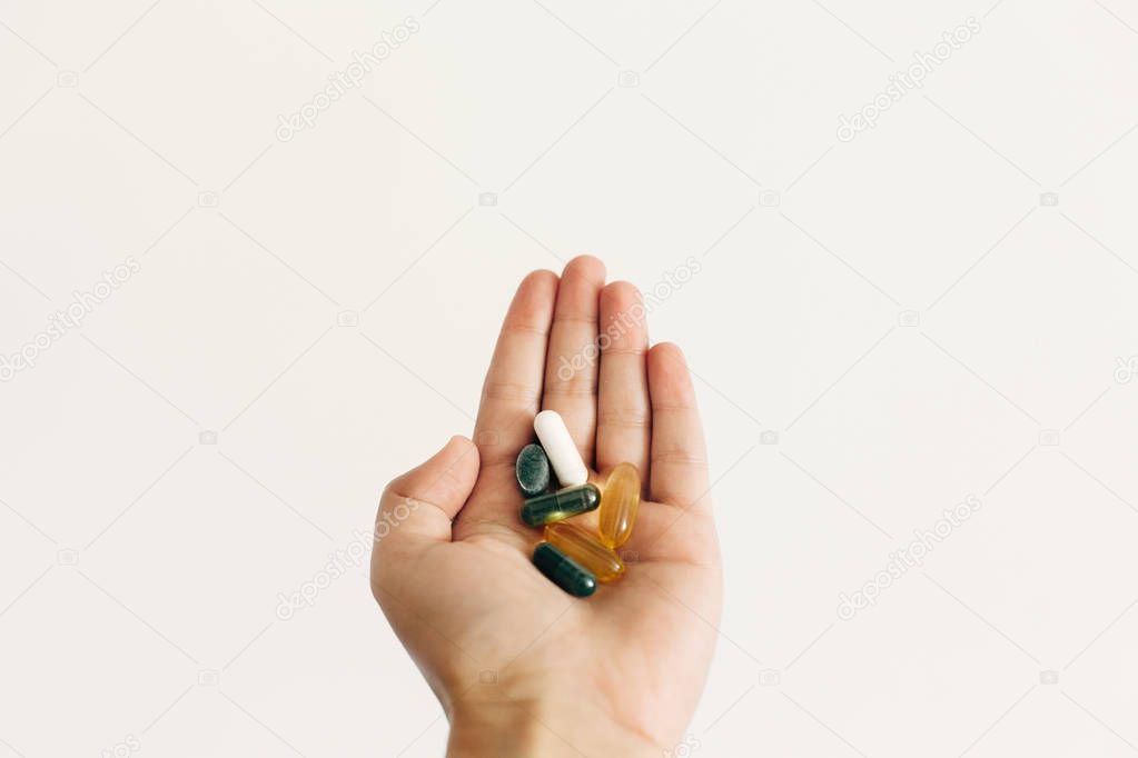 Hand holding omega 3, spirulina, chlorophyll,magnesium  capsules