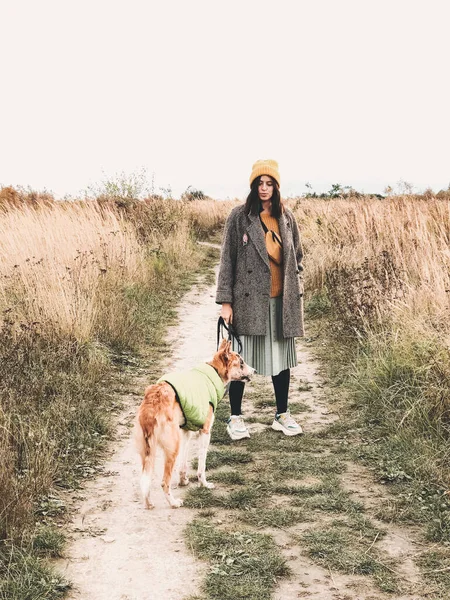 Hipster girl in yellow hat and in coat walking with her golden d — Stock Photo, Image