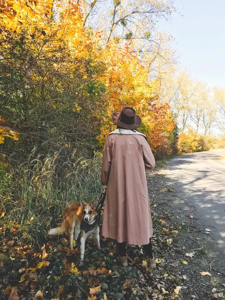 Hipster-Frau, die mit ihrem goldenen Hund unterwegs ist und im Herbst spazieren geht — Stockfoto