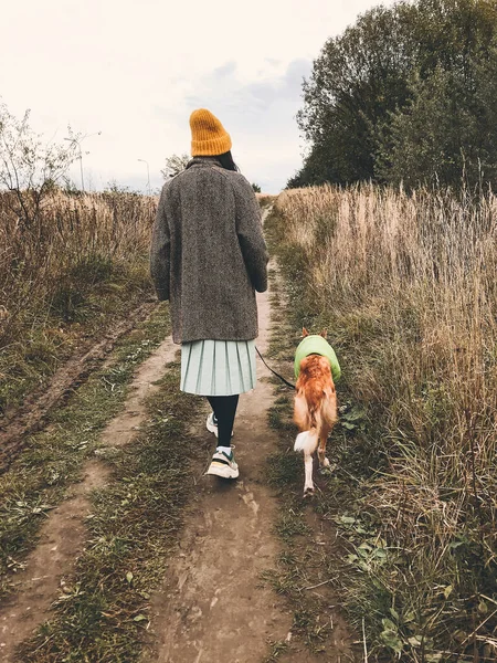 Hipster chica en sombrero amarillo y en abrigo caminando con su d de oro —  Fotos de Stock