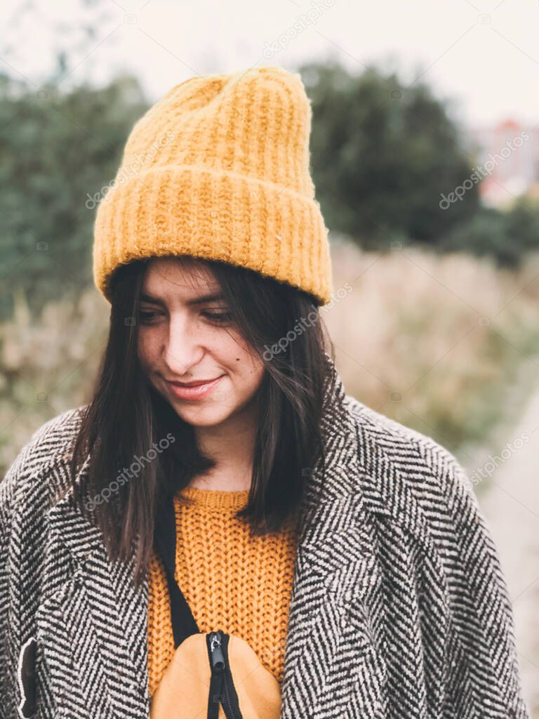 Portrait of beautiful hipster girl in yellow hat and brown coat 