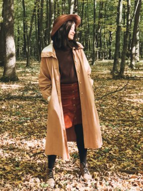 Sonbahar güneşli ormanlarında gezen şapkalı ve paltolu hippi kadın...