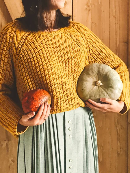 Gadis hipster dengan sweater kuning memegang labu di atas kayu pedesaan — Stok Foto