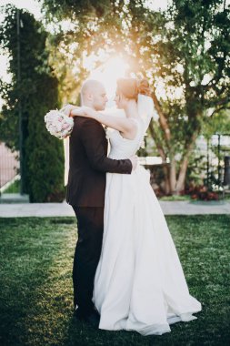 Muhteşem gelin ve damat gün batımında nazikçe sarılıyorlar. Çok güzel.