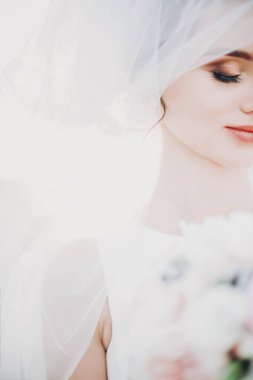 Duvağın altında elinde buketle güzel bir gelinin şehvetli portresi.