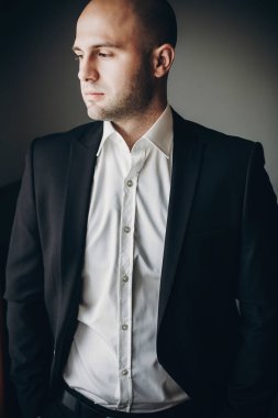 Odanın penceresine yakın duran siyah takım elbiseli şık bir damat. Gizle