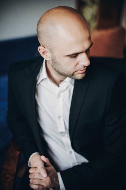 Siyah takım elbiseli şık damat sabahleyin hazırlanıyor.