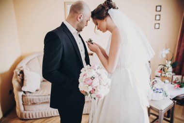 Güzel gelin şık bir yaka çiçeğini damat elbisesine koyuyor, ayağa kalk