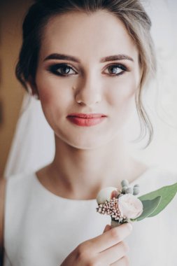 Güzel şehvetli gelin elinde şık bir yaka çiçeğiyle, yanında poz veriyor.