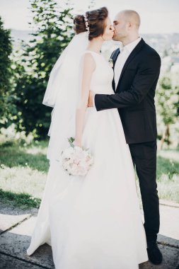 Tarz sahibi gelin ve damat dışarıda nazikçe öpüşüyor. Güzel gelin.