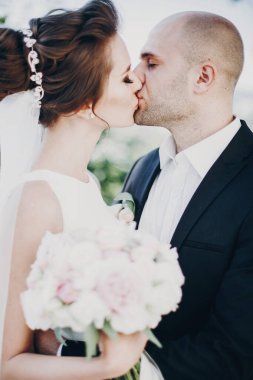 Tarz sahibi gelin ve damat dışarıda nazikçe öpüşüyor. Güzel gelin.