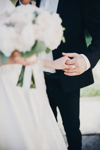 Πανέμορφη νύφη και γαμπρός απαλά κρατώντας τα χέρια στο πάρκο το βράδυ. Κ — Φωτογραφία Αρχείου