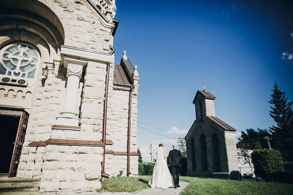 Snyggt bröllopspar som går i kyrkan efter vigseln. G — Stockfoto