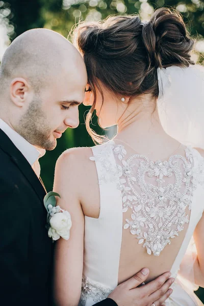 A vőlegény gyengéden megcsókolja a gyönyörű menyasszonyt napnyugtakor. Gyönyörű. — Stock Fotó