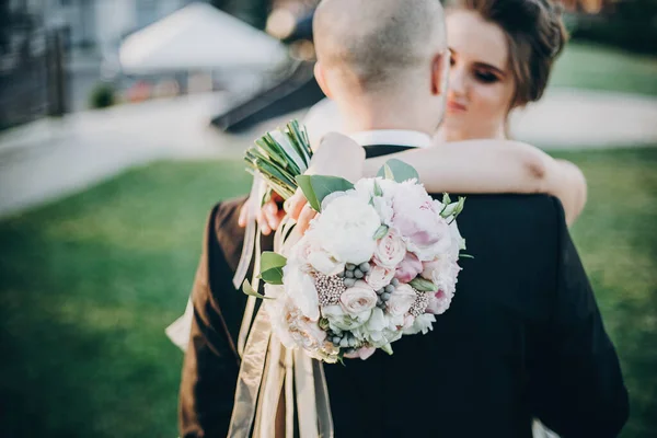 Moderní svatební kytice v rukou nevěsty. Nádherná nevěsta něžně objímá — Stock fotografie