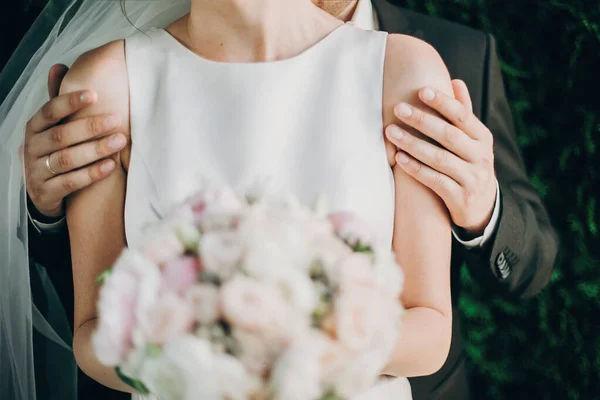 Stylish groom gently hugging gorgeous bride shoulders in summer — Stock Photo, Image