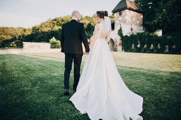 Πανέμορφη νύφη και γαμπρός περπατούν στο φως του ήλιου. Όμορφη Στυλ. — Φωτογραφία Αρχείου
