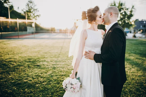 Стильна наречена і наречений м'яко цілуються під час заходу сонця. Боутіту — стокове фото