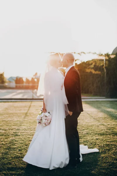 Mariée élégante et marié embrassant doucement dans la lumière du coucher du soleil. Beautifu — Photo