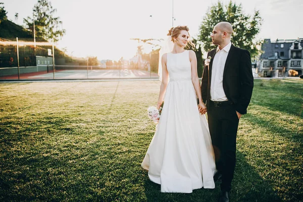 Hermosa novia y novio caminando en la luz del atardecer. Hermoso estilo —  Fotos de Stock