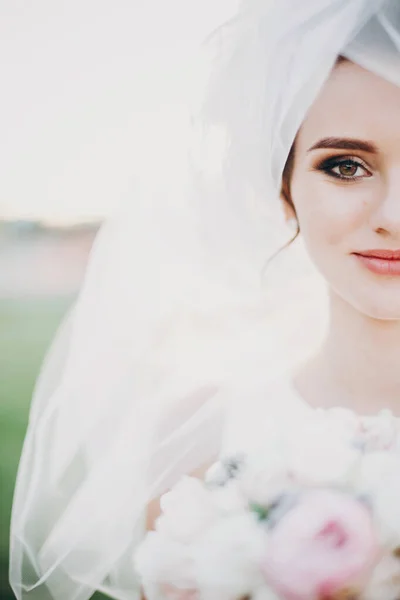 Αισθησιακό πορτρέτο της όμορφης νύφης κάτω από πέπλο κρατώντας μπουκέτο o — Φωτογραφία Αρχείου